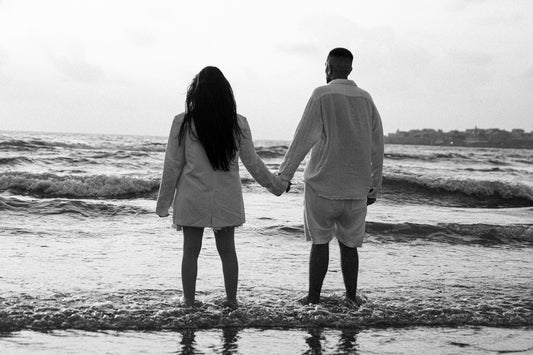 a man and a woman holding hands while standing in the ocean