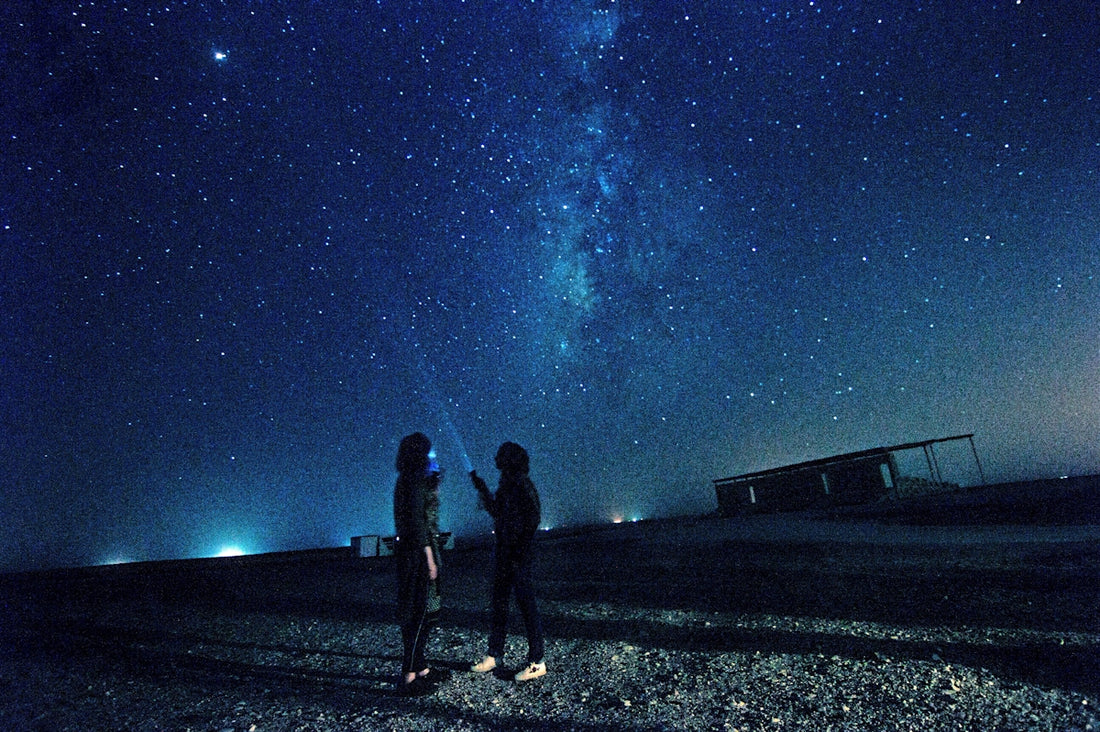 A couple of people standing next to each other under a sky filled with stars