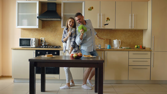 Couple dancing in a modern kitchen with food.