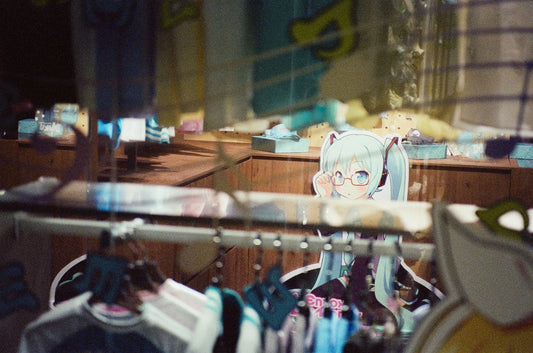 Anime character with glasses and pigtails peeking over counter