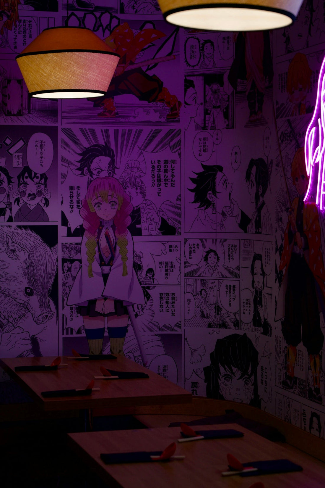 Anime manga wallpaper adorns a dimly lit restaurant interior.